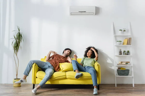 Sweaty Multiethnic Couple Sitting Yellow Sofa Suffering Heat Summer — Stock Photo, Image