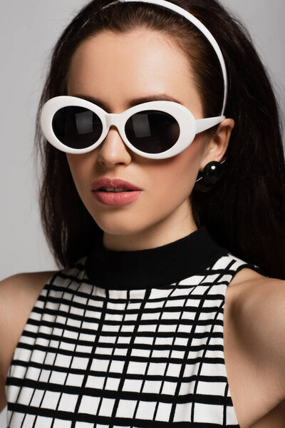 trendy young model in sunglasses and headband isolated on grey 