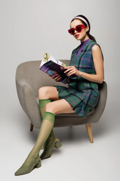 Junge Frau Mit Sonnenbrille Liest Magazin Und Sitzt Sessel Auf — Stockfoto