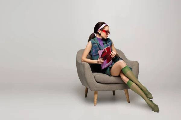 Jeune Femme Lunettes Soleil Bandeau Tenant Magazine Assis Dans Fauteuil — Photo