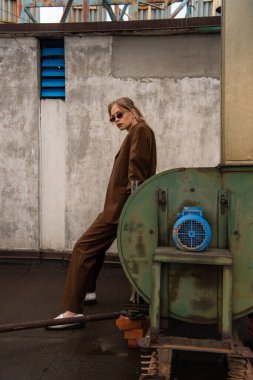 Şık güneş gözlüklü ve çatıda poz veren modaya uygun genç bir model.