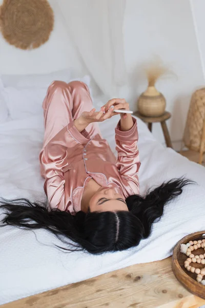 Young Asian Woman Silk Pajamas Lying Bed Cellphone Bedroom — Stock Photo, Image