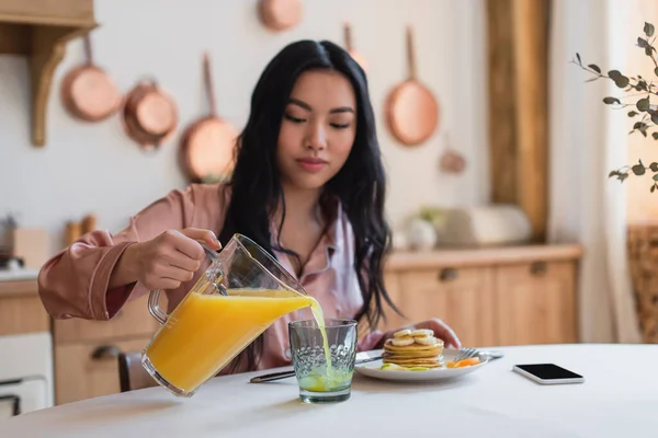 Young Asian Woman Silk Pajamas Pouring Orange Juice Glass Pancakes — Stock Photo, Image