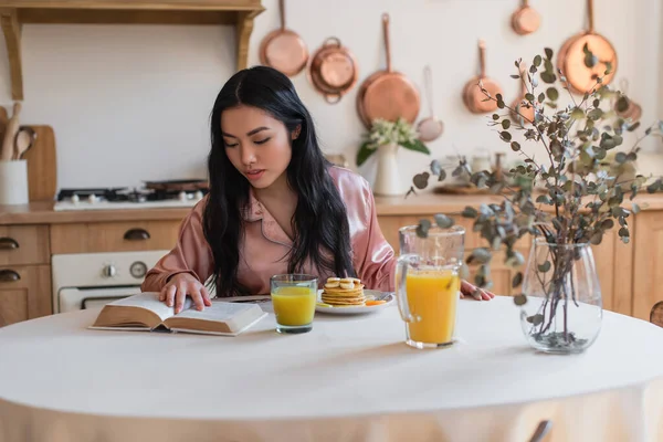 Young Asian Girl Silk Pajamas Reading Book While Having Breakfast — Stock Photo, Image