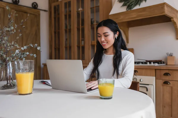 Smiling Young Asian Woman Earphones Sitting Table Using Laptop Kitchen — Stock Photo, Image