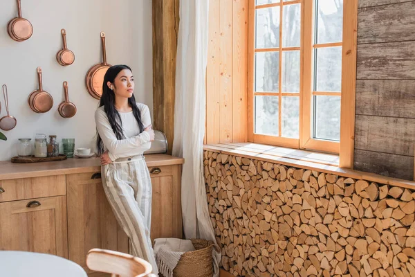 Thoughtful Young Asian Woman Earphones Standing Crossed Hands Kitchen — Stock Photo, Image