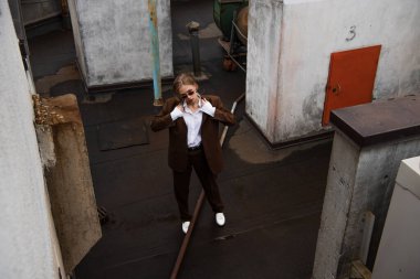 Çatıda şık sarışın bir kadının tişörtünü ayarlarken yüksek açılı görüntüsü. 