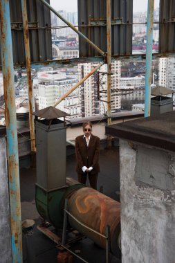 Yüksek açılı, güneş gözlüklü şık sarışın kadın çatıda dikiliyor. 