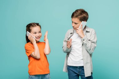 Akıllı telefondan konuşan çocuk Grey 'de izole edilmiş cep telefonlu mutlu kıza bakıyor.