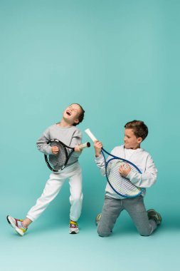 amazed kids holding tennis rackets while singing and pretending performing on blue clipart