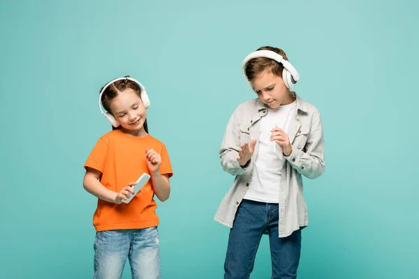 Glimlachende Kinderen Draadloze Hoofdtelefoons Luisteren Muziek Houden Smartphones Geïsoleerd Blauw — Stockfoto