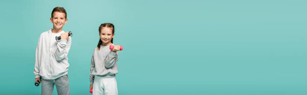 happy kids in sportswear working out with dumbbells isolated on blue, banner