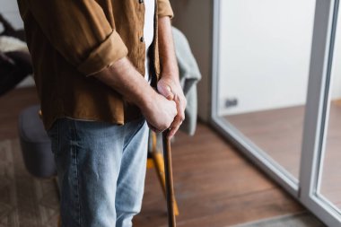 Cropped view of senior man holding crutch at home  clipart