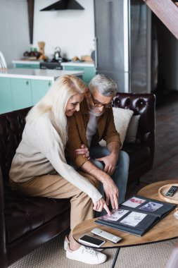 Elderly couple looking at photos in album at home 