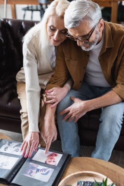 Elderly couple looking at photos in album on couch
