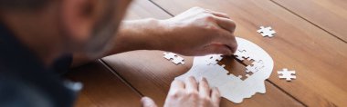 Cropped view of blurred man with dementia folding puzzle, banner 