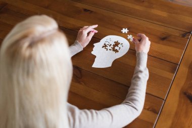 Overhead view of senior woman with dementia folding jigsaw clipart
