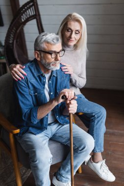 Blurred woman calming husband with crutch 