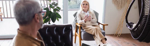 Alegre Anciana Usando Teléfono Inteligente Sillón Cerca Marido Borroso Sala — Foto de Stock