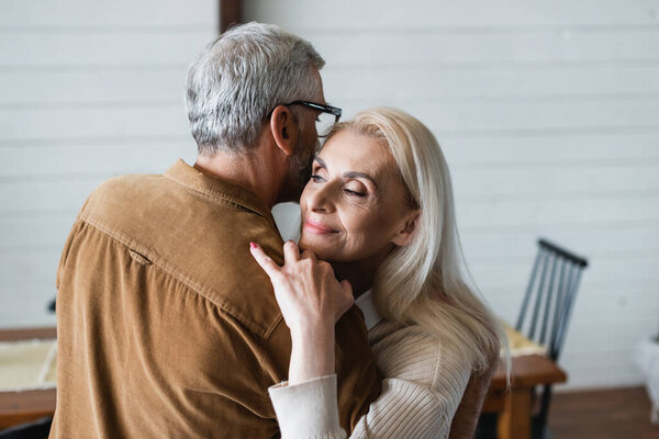 Smiling woman embracing husband in eyeglasses 