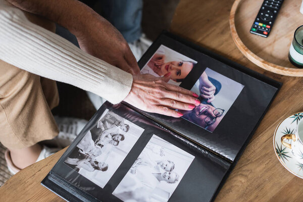 Cropped view of senior couple sitting near photo album and cup on table