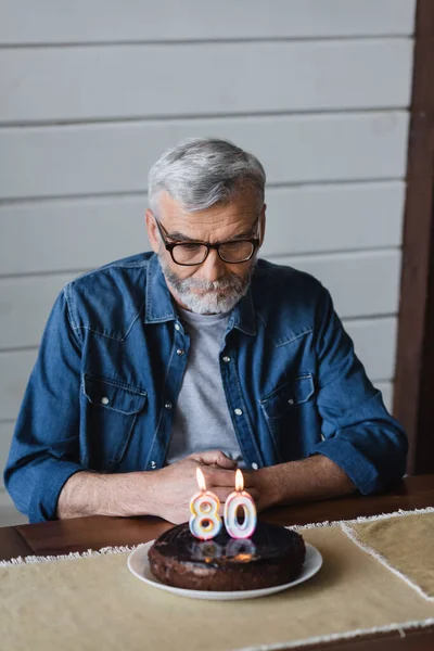 Homem Sênior Olhando Para Bolo Aniversário Borrado Mesa — Fotografia de Stock