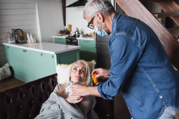 Marido Borroso Máscara Médica Sosteniendo Agua Pastillas Cerca Esposa Casa — Foto de Stock