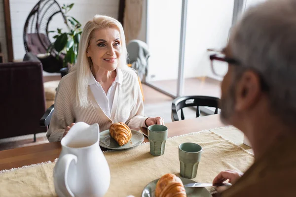 Mujer Mayor Sonriente Mirando Marido Borroso Cerca Del Desayuno — Foto de Stock