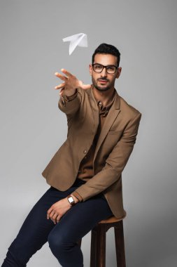 Arap işadamı gri üzerine kağıt uçak fırlatıyor. 