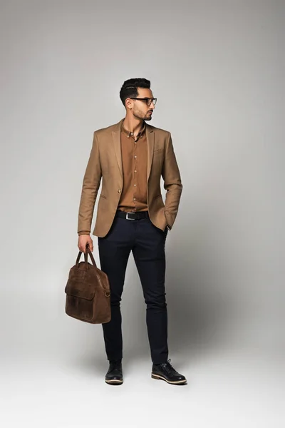 Arabian businessman with handbag looking away on grey background