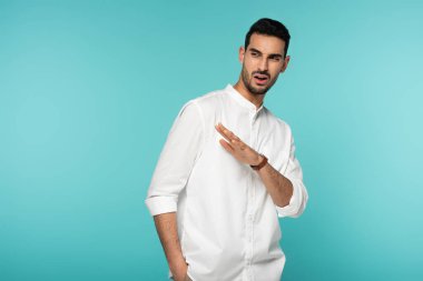 Kafası karışmış Müslüman adam mavi üzerine el işaretleriyle işaret ediyor. 
