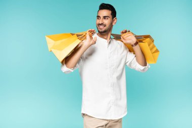 Genç müslüman alışveriş meraklısı gülümseyerek alışveriş çantalarını mavi renkte soyutladı. 