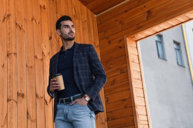 Açık havada kot pantolon ve kağıt bardak cebinde el ele tutuşan Arap işadamı. 