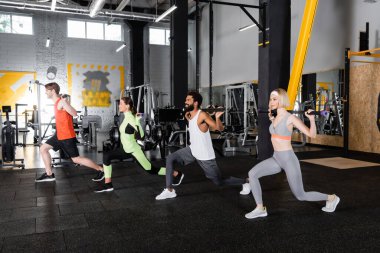 Genç çok ırklı sporcular jimnastik sopalarıyla ileri atılıyorlar. 