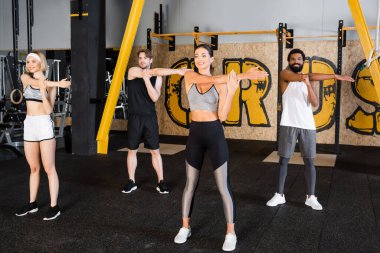 gülümseyen etnik çeşitlilikte insanlar spor salonunda birlikte esniyorlar.