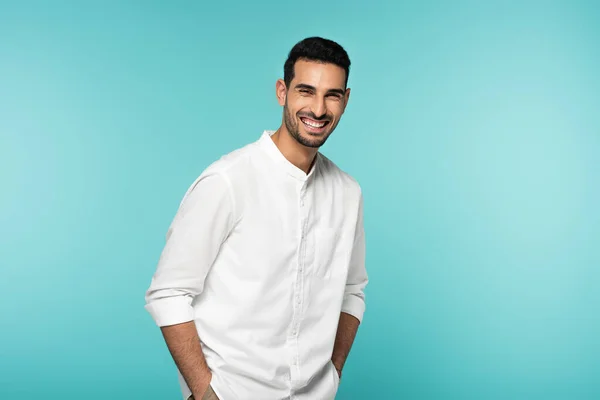 幸せなイスラム教徒の男で白いシャツを見ますカメラで隔離された上の青 — ストック写真