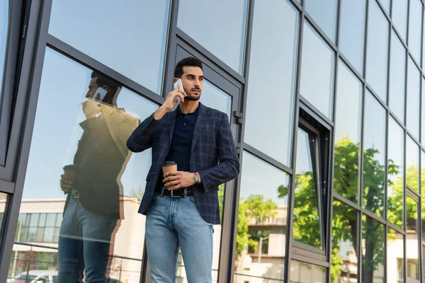 アラビア人のビジネスマンがスマートフォンでコーヒーを飲みながら屋外に出る — ストック写真
