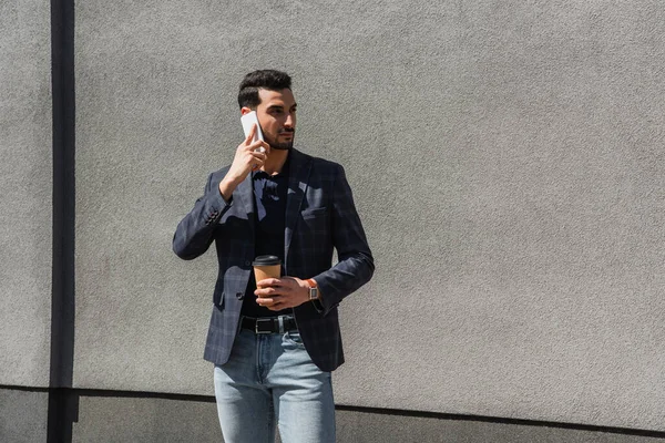 Muslim Man Jacket Holding Paper Cup Talking Smartphone Concrete Wall — Zdjęcie stockowe