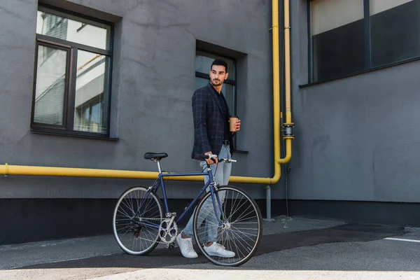 Μουσουλμάνος Διαχειριστής Χάρτινο Κύπελλο Και Ποδήλατο Περπατώντας Κοντά Στο Κτίριο — Φωτογραφία Αρχείου
