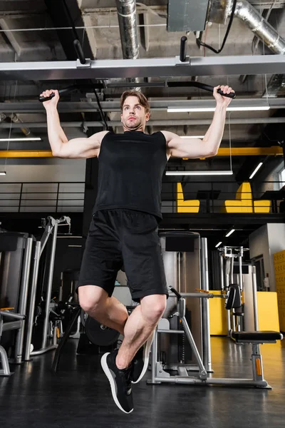 young man in black sportswear training on horizontal bar