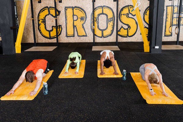 sports group training in seated forward bend pose on fitness mats