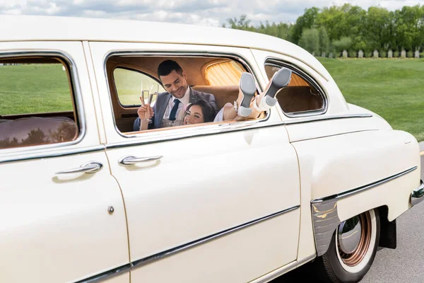 Sorrindo Noiva Segurando Champanhe Perto Noivo Carro Retro — Fotografia de Stock