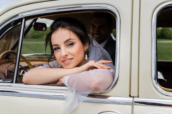 Novia Alegre Velo Blanco Mirando Cámara Cerca Ventana Del Coche —  Fotos de Stock