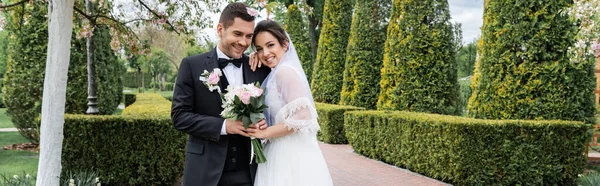 Smiling Bride Holding Bouquet Hugging Groom Park Banner — Stock Photo, Image