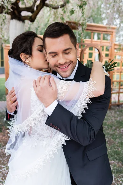 Bride Veil Kissing Hugging Smiling Groom Closed Eyes Park — Stock Photo, Image