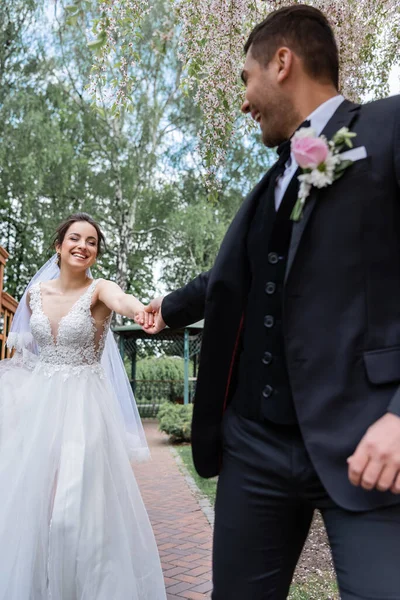 Glimlachende Bruid Houdt Hand Hand Van Wazige Bruidegom Park — Stockfoto