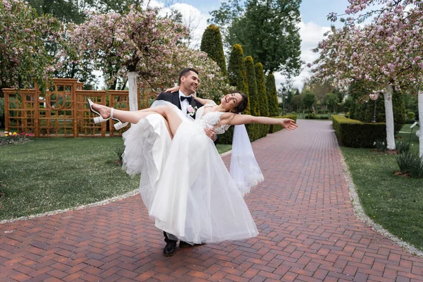 Happy Groom Holding Hands Bride Closed Eyes Walkway Park — Stock Photo, Image