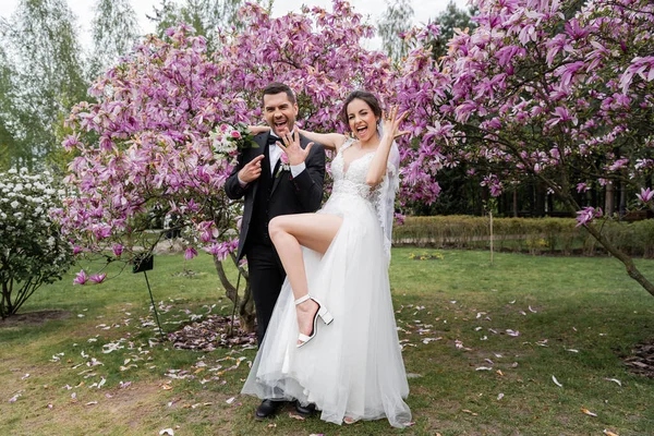 Vrolijke Pasgetrouwden Tonen Ringen Buurt Van Magnolia Bomen Park — Stockfoto