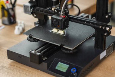 3D printer creating plastic model on table in modern office