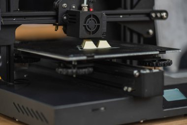 close up view of 3D printer creating plastic model on blurred background